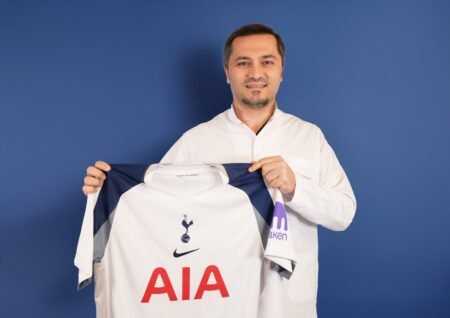 Bild zeigt, wie Dr. Abdulaziz Balwi ein Trikot des Premier-League-Klubs Tottenham Hotspur in beiden Händen hält